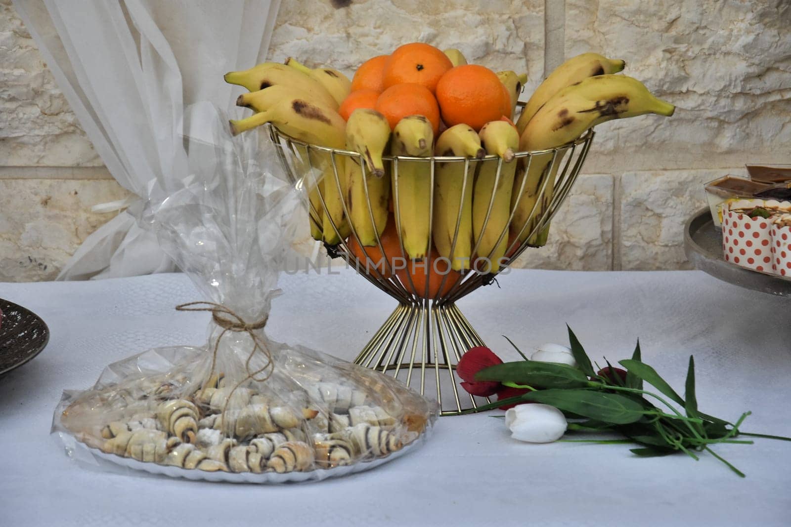 cakes on a platter, bananas in a vase on a table with a white tablecloth. High quality photo