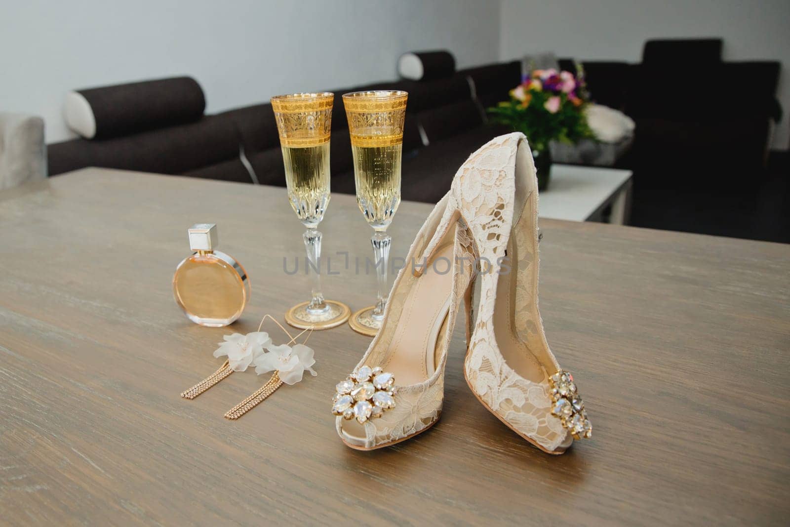 Set bride's accessories: perfume bottle, earrings, two glasses of champagne and women's shoes. Soft focus.