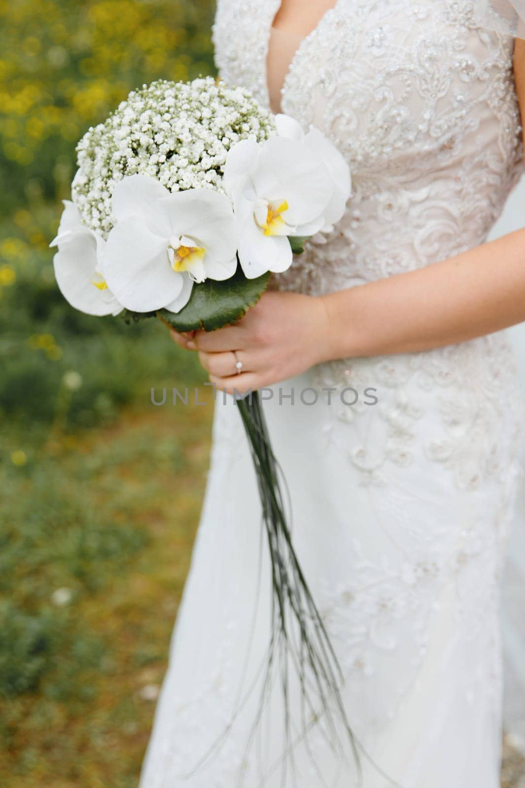 The bride is holding a wedding bouquet. No face.