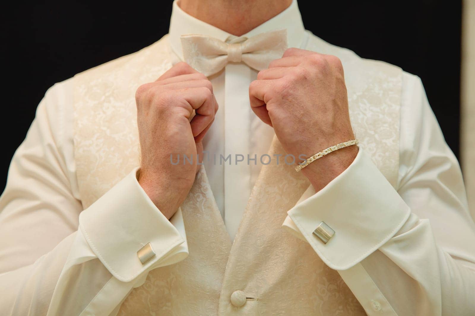 Man fixing his bow tie. Man groom in wedding suit with a bow tie. Close-up. by leonik