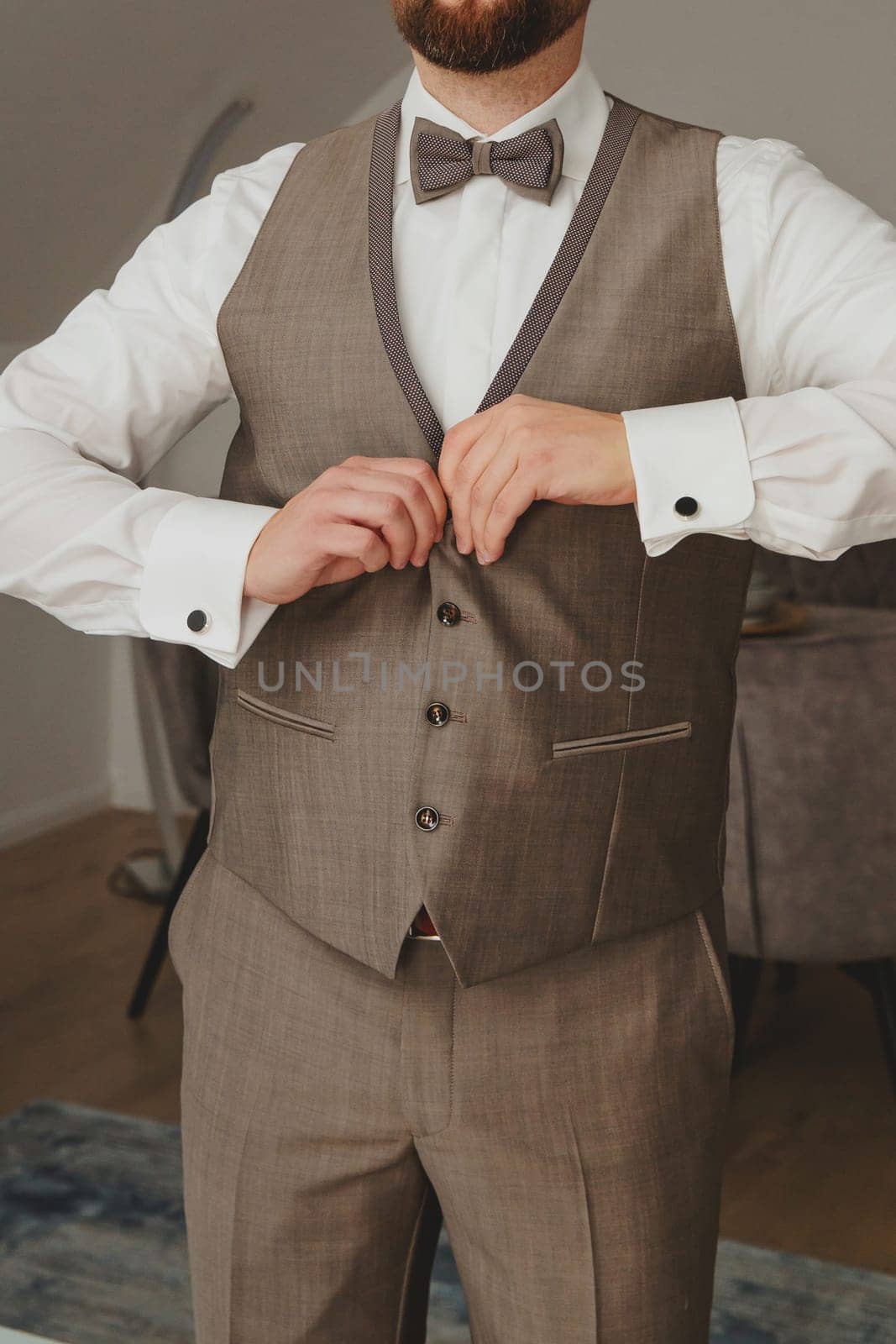 Groom buttons up the front of the waistcoat. by leonik