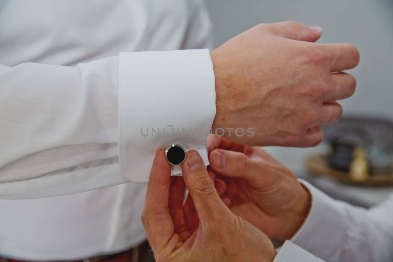 A groom putting on cuff-links. Groom's suit. by leonik