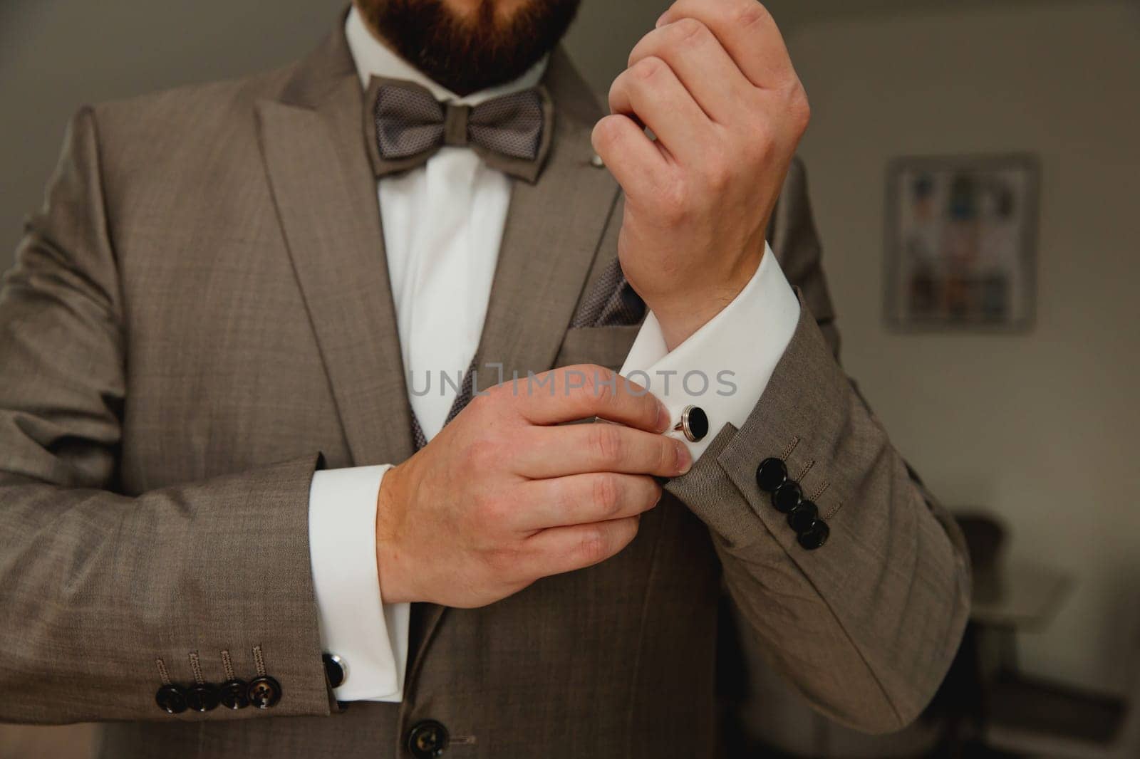 A groom putting on cuff-links. Groom's suit.