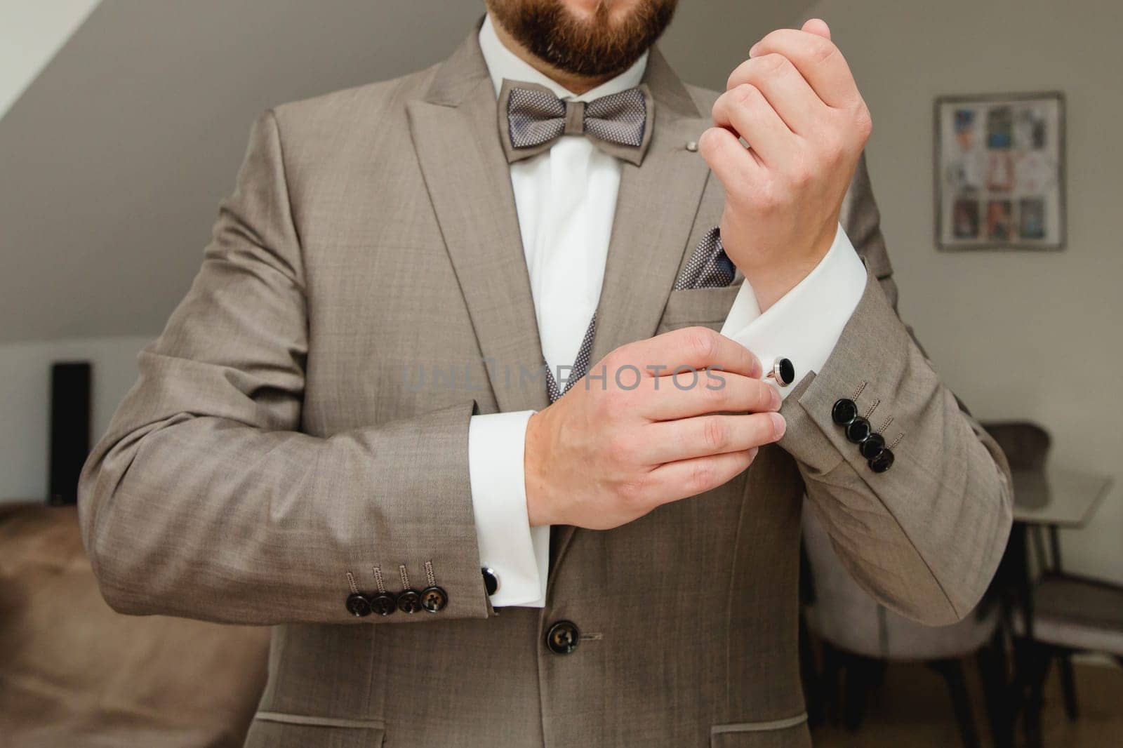 A groom putting on cuff-links. Groom's suit.