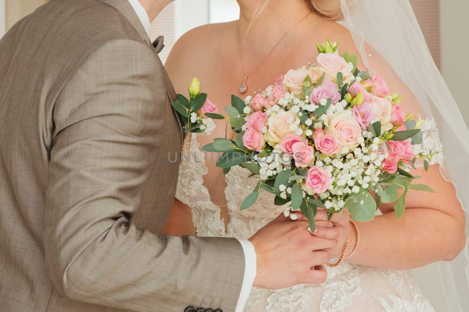 The couple embracing each other holding a bouquet. Close-up.