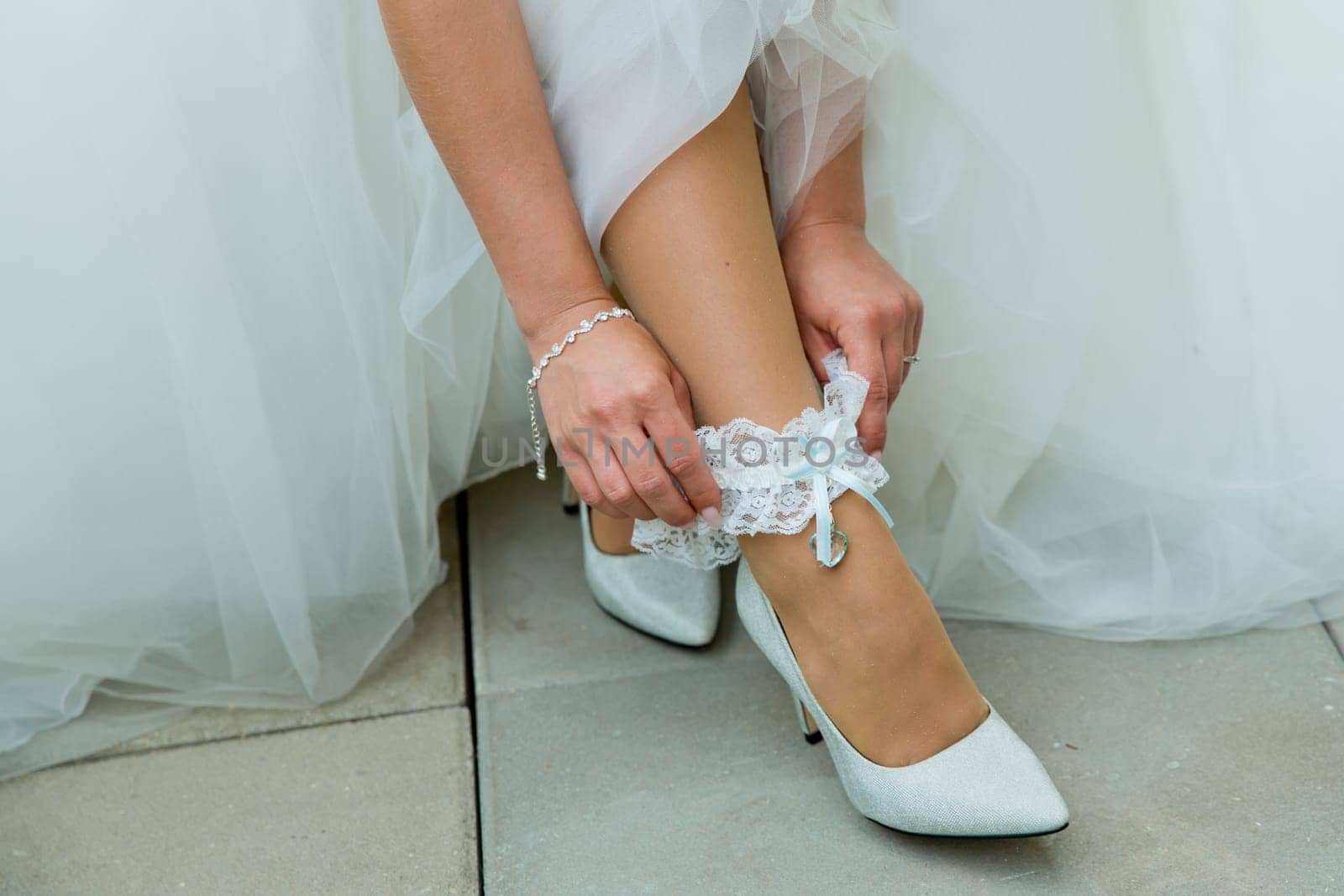 The bride adjusts the garter on her leg. by leonik