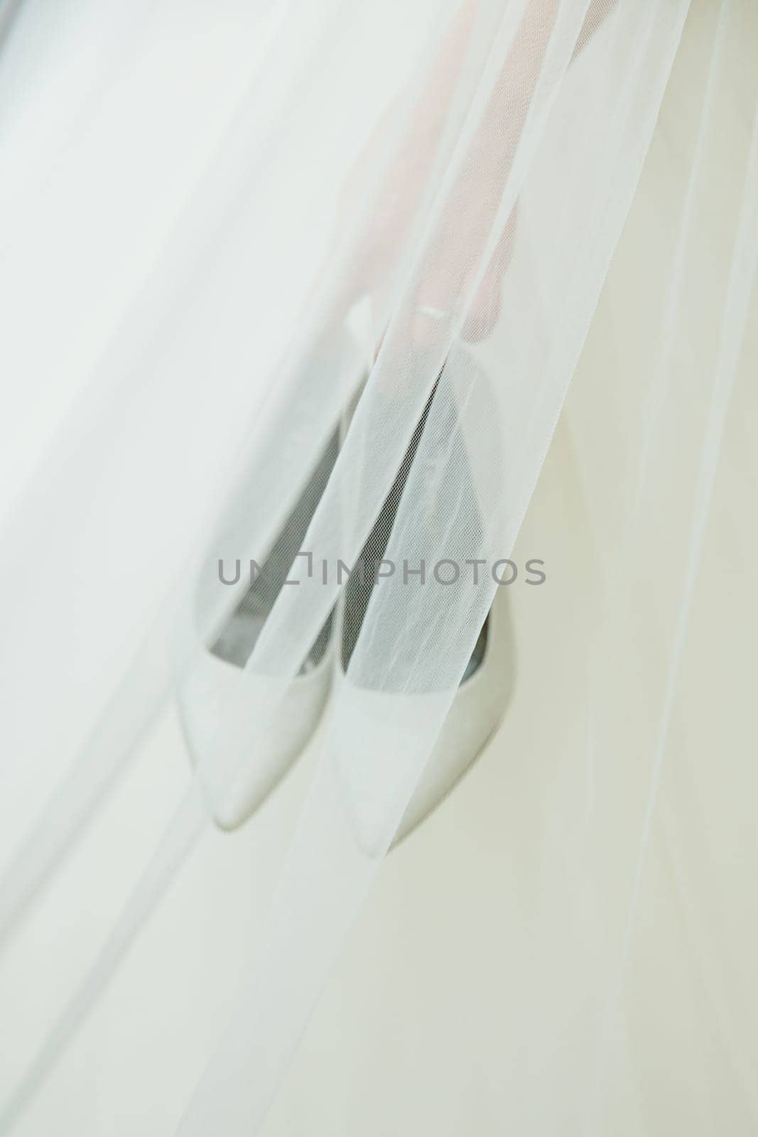 The bride holds wedding shoes in her hands.