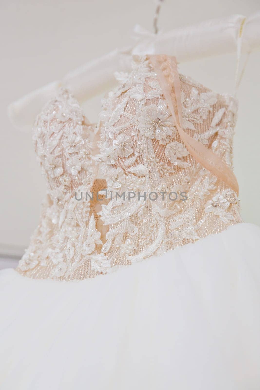 The delicate bride's dress is hanging in room. Selective focus. Close-up.