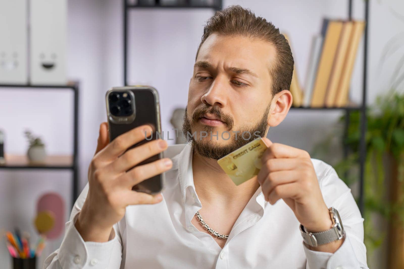 Bearded businessman programmer software developer working making online purchase payment shopping with credit bank card and use laptop at home office desk with laptop. Lebanese freelancer business man