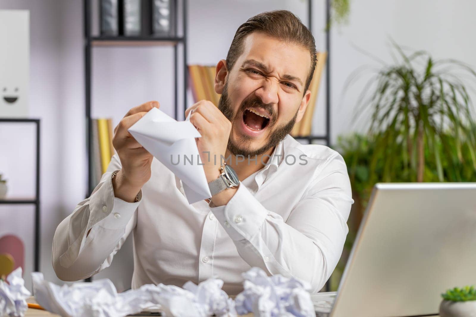 Angry furious businessman working at office throwing crumpled paper, having nervous breakdown at work, migaine, headache, stress management, mental distress problems, losing temper reaction on failure