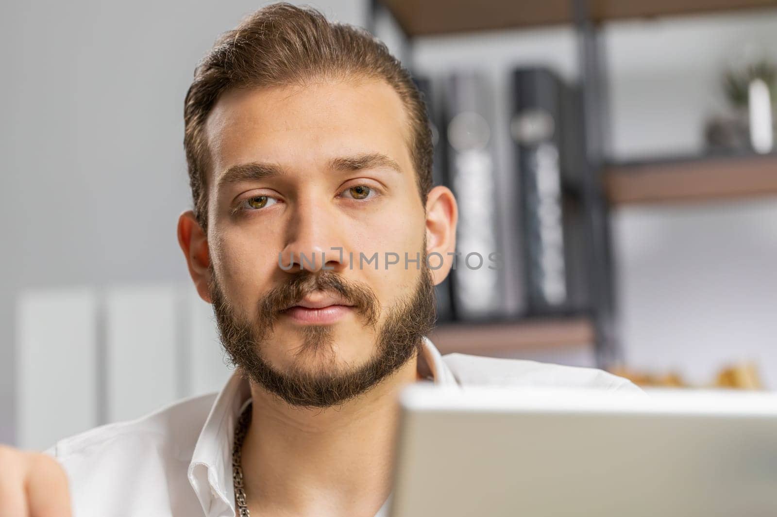 Close-up portrait bearded businessman face freelancer at home office workplace working on laptop computer. Manager freelancer middle eastern man works on notebook send messages makes online purchases