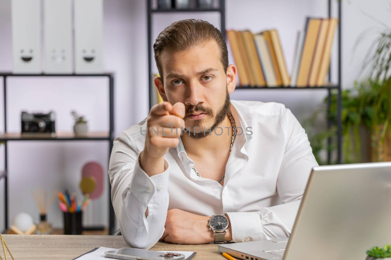 I choose you. Middle eastern businessman programmer software developer working on office laptop pointing to camera, looking with happy expression, making choice, showing direction. Arab freelancer man