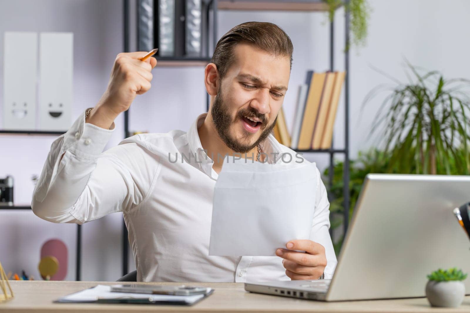 Lebanese business man open envelope letter, reading it. Career growth advance promotion, bank loan approve, successful admission to monetary award, long-awaited invitation, great lottery game win news