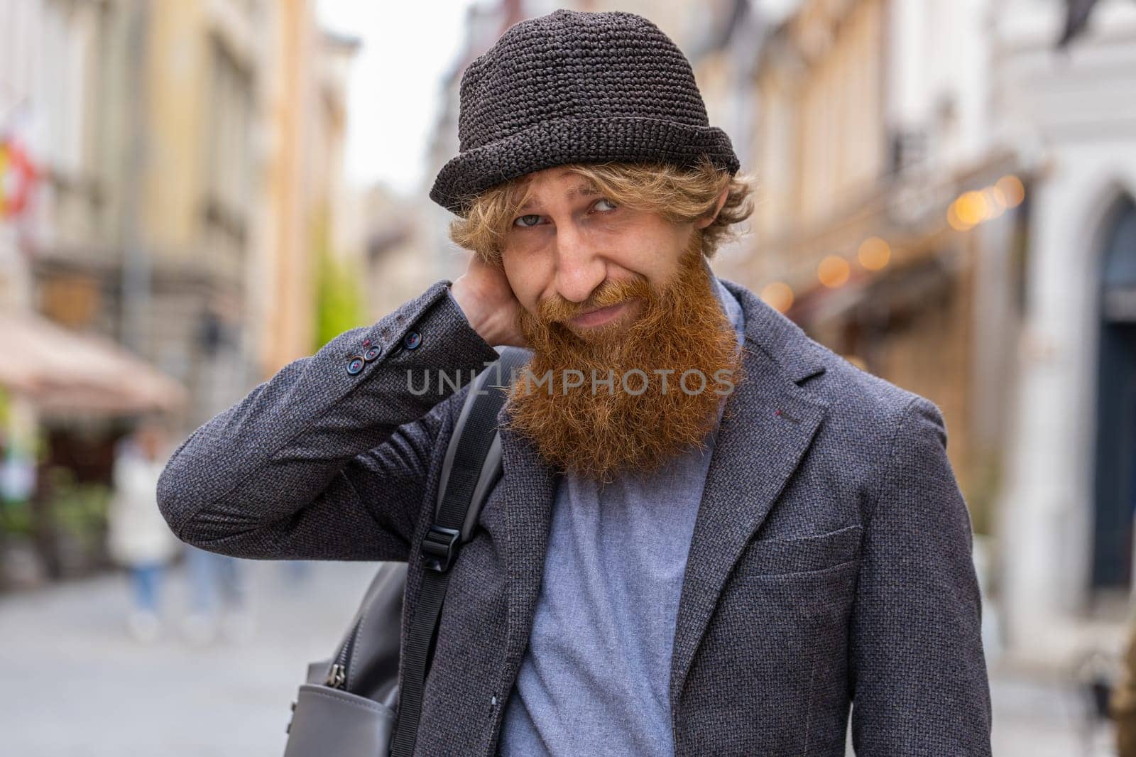 Sad unhappy young bearded man thinks over life concerns, suffers from unfair situation. Problem, feeling bad, annoyed, burnout, grief. Frustrated depressed lonely redhead guy walking in city street