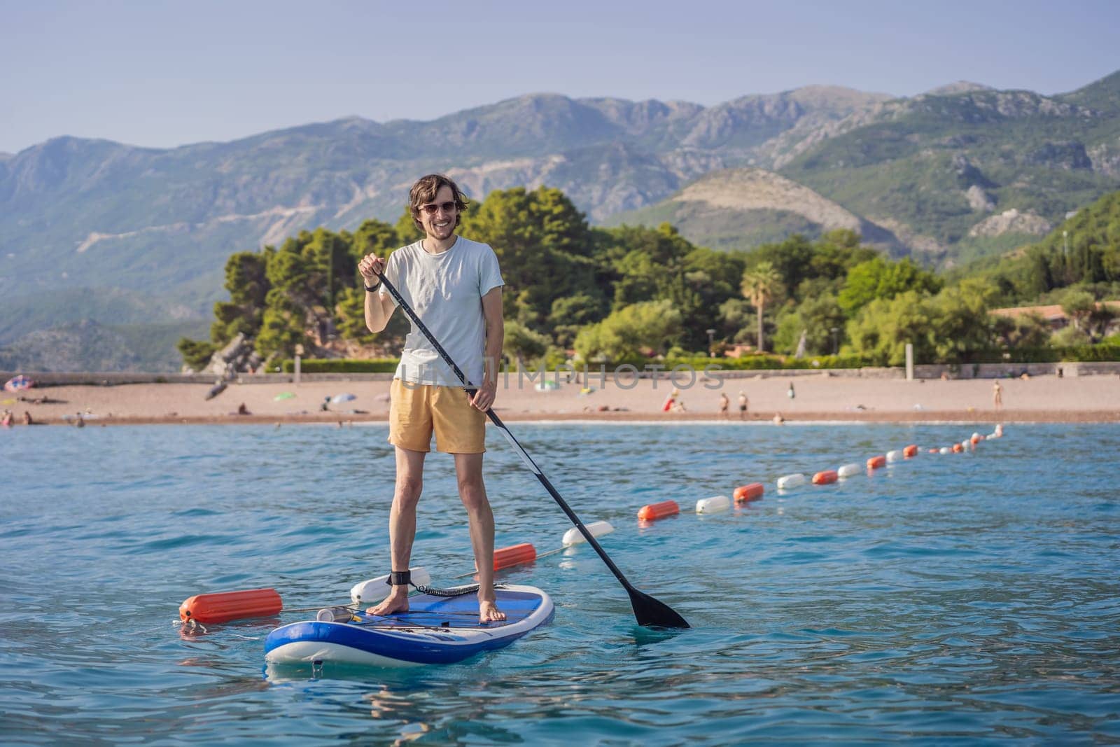 Young men Having Fun Stand Up Paddling in blue water sea near st stefan island in Montenegro. SUP.