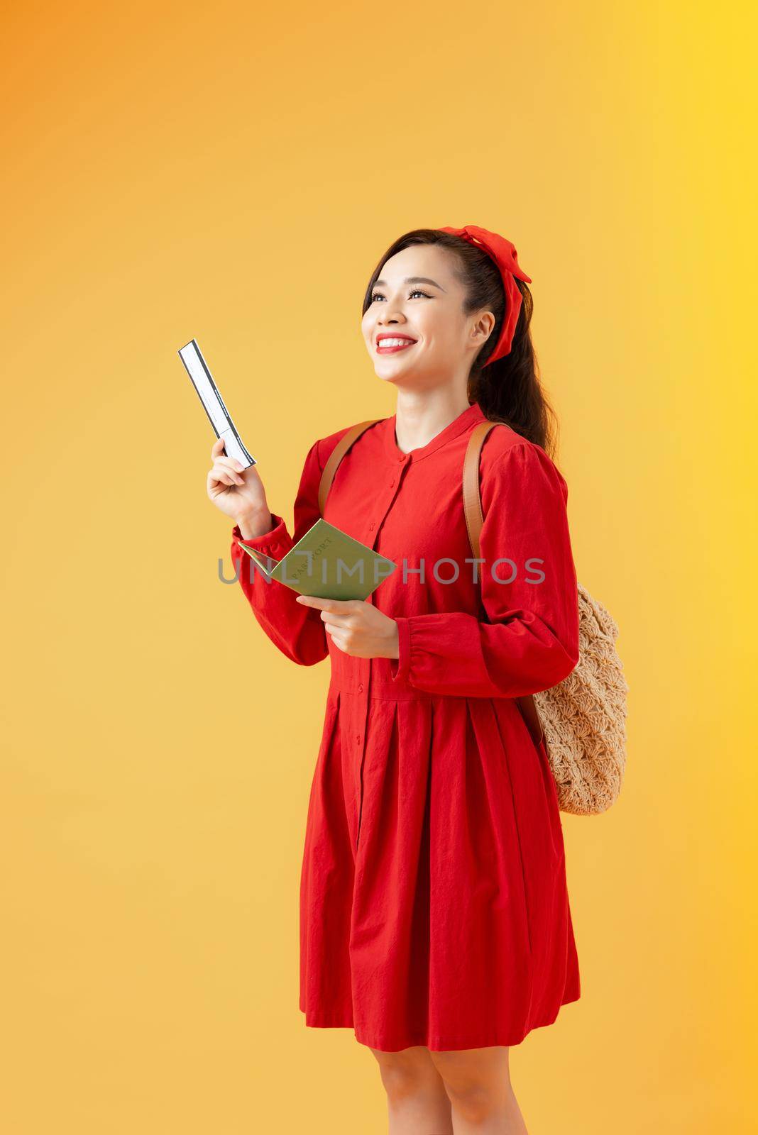 Happy young woman holding tickets and passport to travel isolated on orange background. by makidotvn