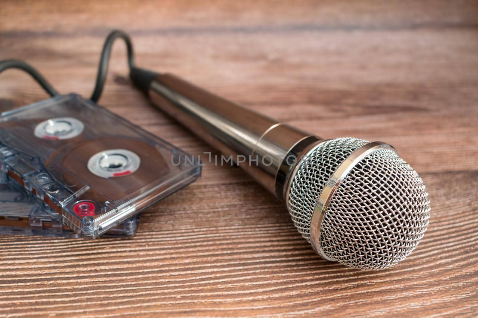 Silver microphone and and old magnetic audio cassettes, objects of bygone times