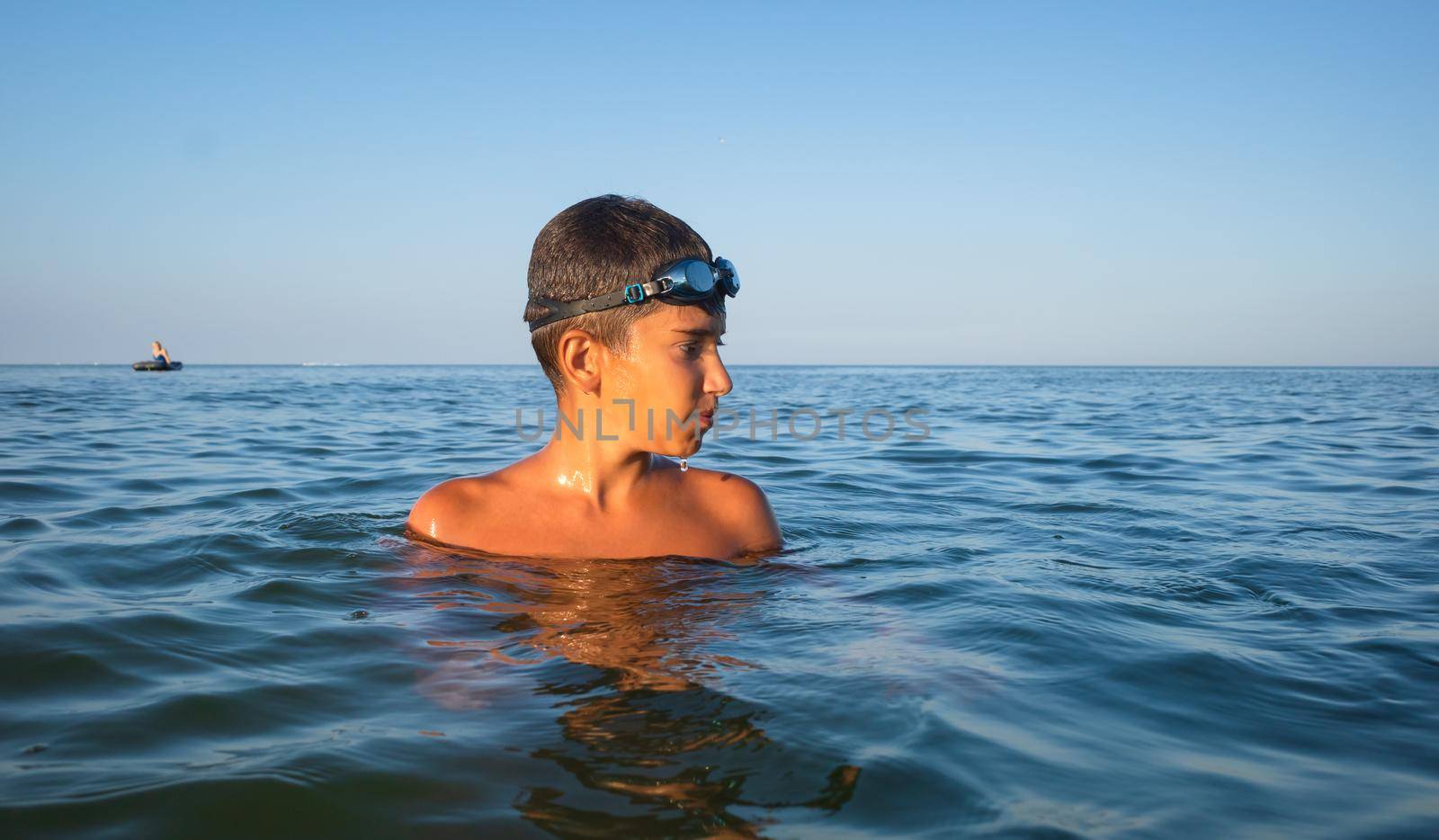 Relaxation and healthy lifestyle. Young boy teenager bathes in the sea.