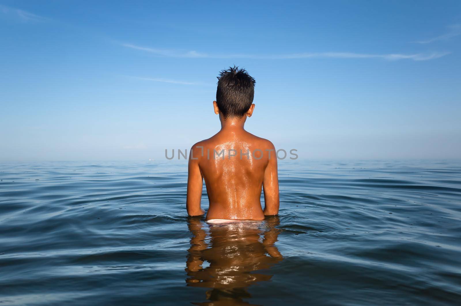 Relaxation and healthy lifestyle. Young boy teenager bathes in the sea.