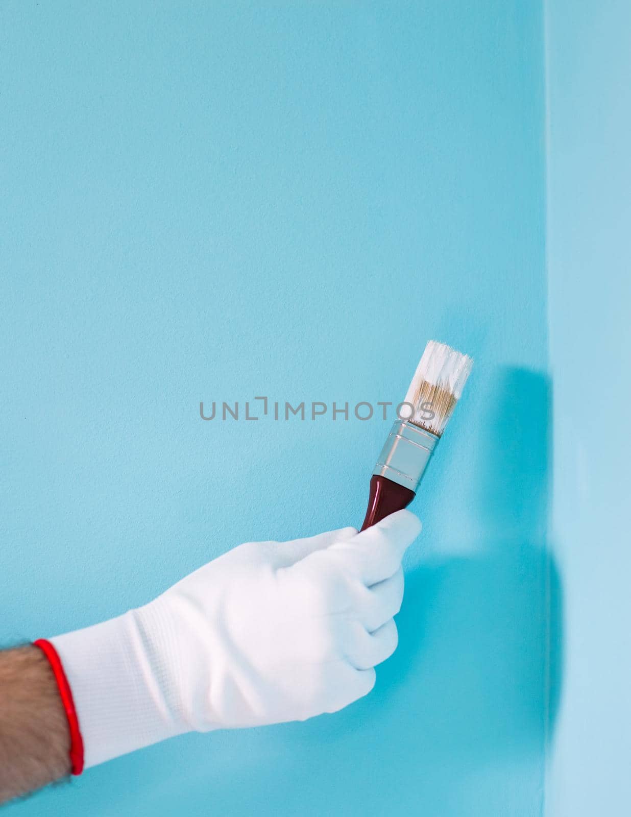 Man holding paintbrush in front of blue wall by Bazdar