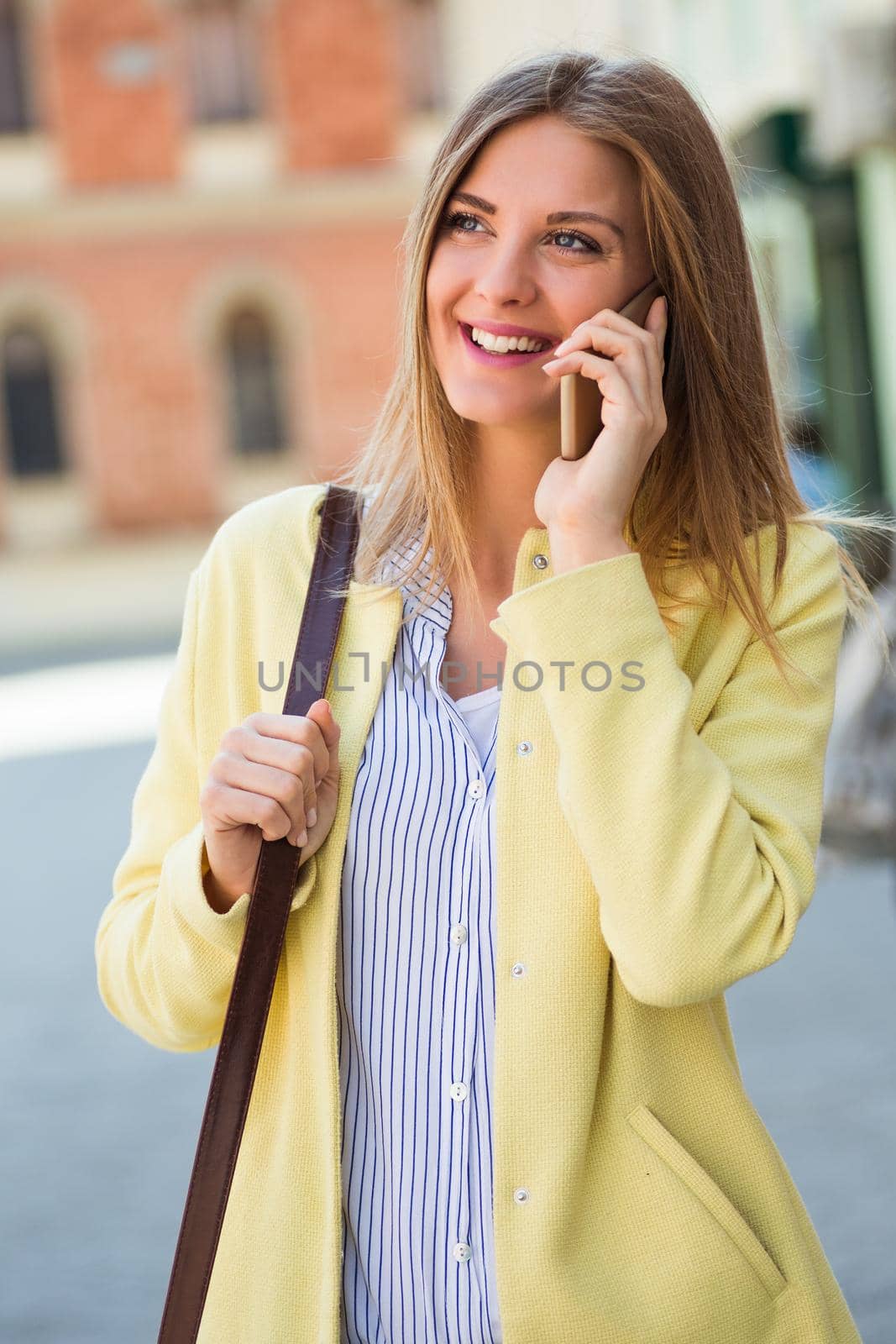 Beautiful young woman talking on the phone at the city.