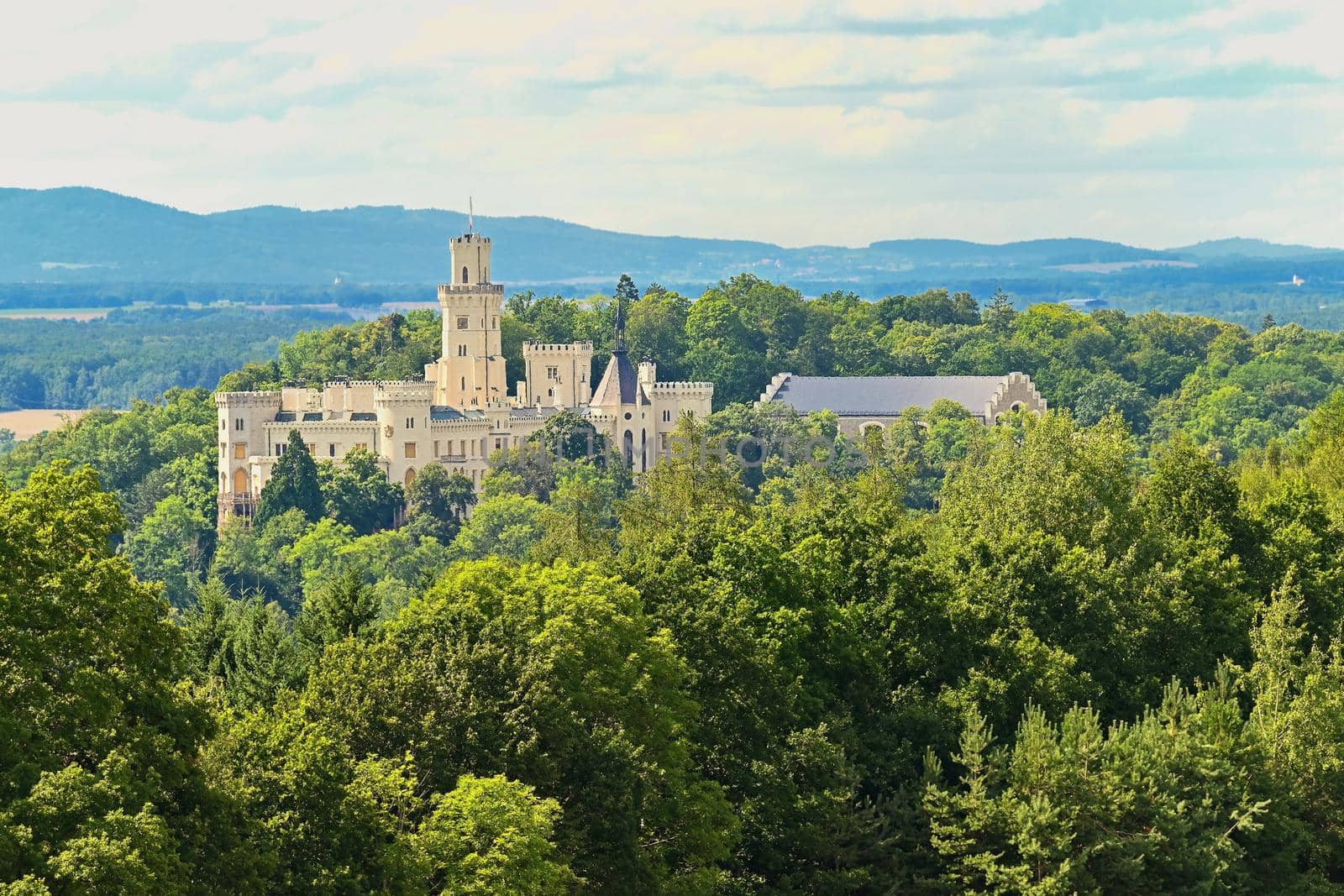 Beautiful old state chateau Hluboká nad Vltavou. View from the outdoor garden in summer with blue sky, sun and clouds.