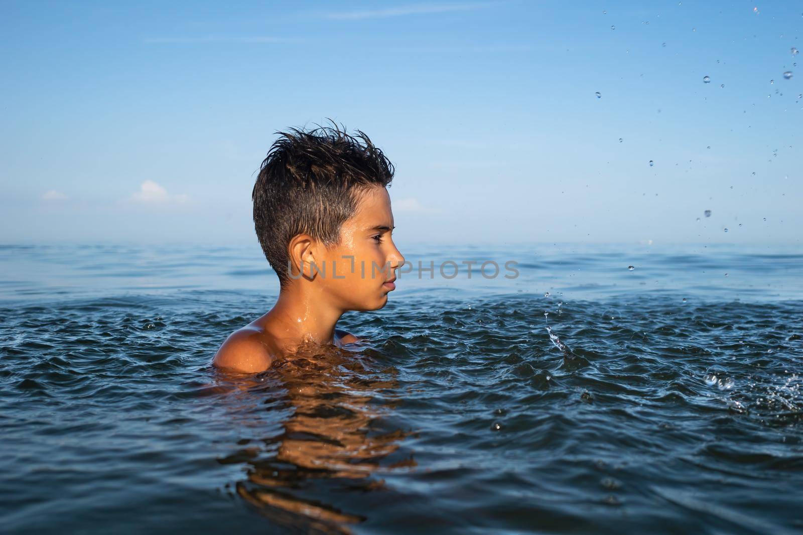 Relaxation and healthy lifestyle. Young boy teenager bathes in the sea.
