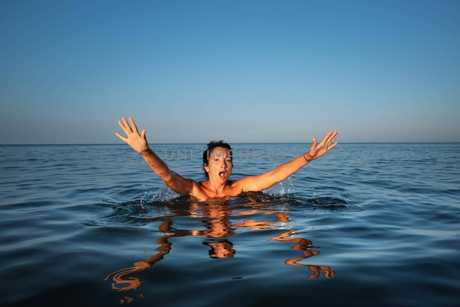 Relaxation and healthy lifestyle. Young beautiful and emotional woman swims in the sea on a sunny day