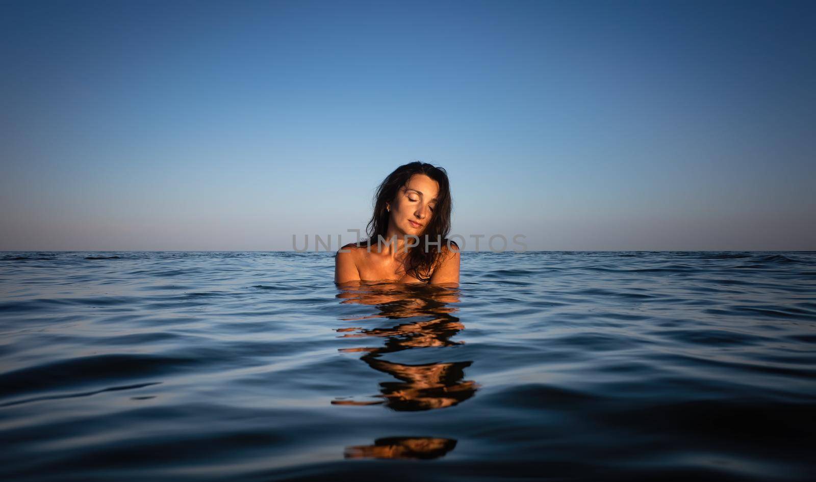 Relaxation and healthy lifestyle. Young beautiful and emotional woman swims in the sea on a sunny day. Portrait in sea water
