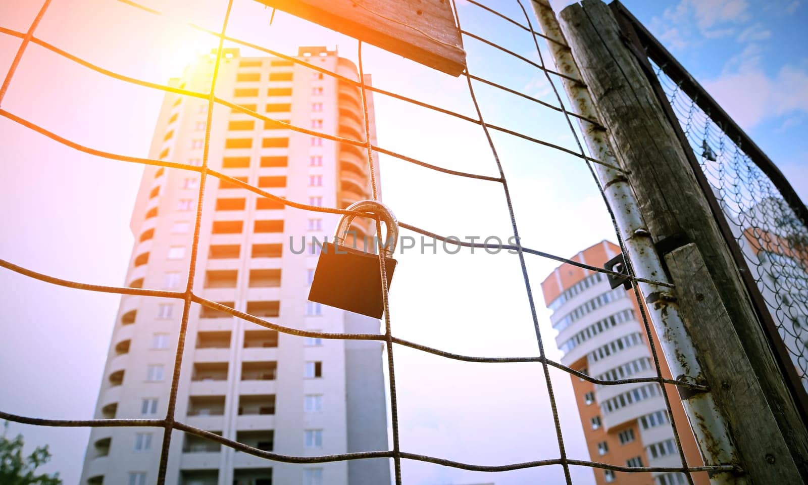 Construction site behind a fence and locked gates. by Hil