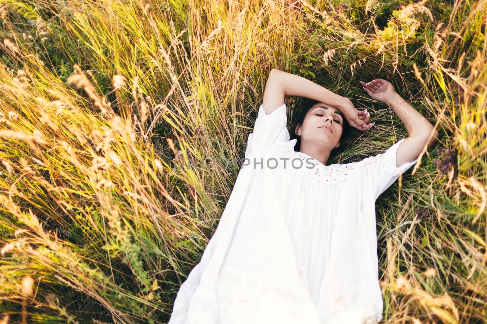Conceived Beautiful young woman lying in the grass, wearing a white dress. Nature, summer holidays, vacation and people concept. by sarymsakov