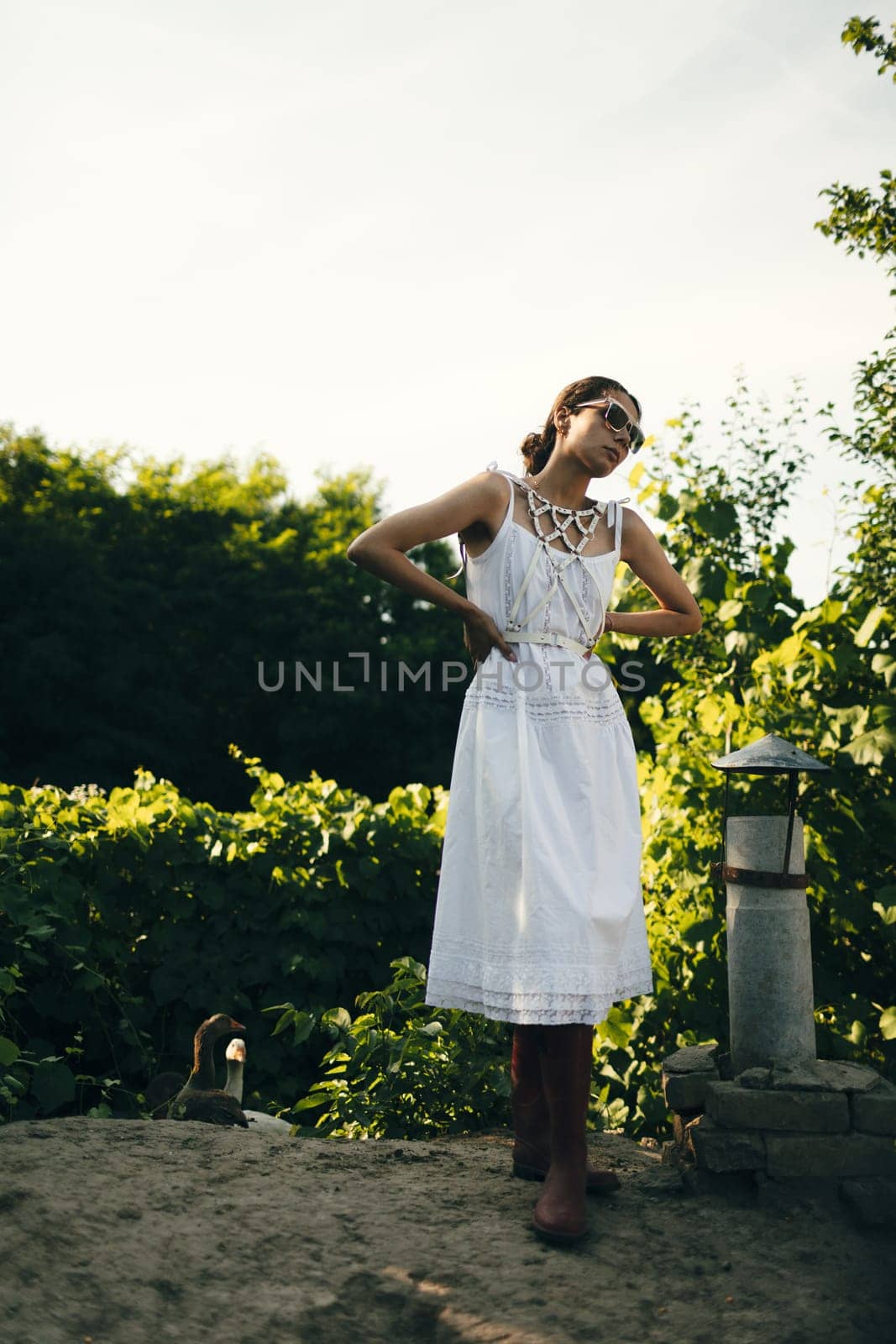 Portrait of a beautiful girl in a white dress in the garden. Burnette beautiful natural girl with in a white dress in nature, on the street, in the garden by a tree, with makeup and hairstyle