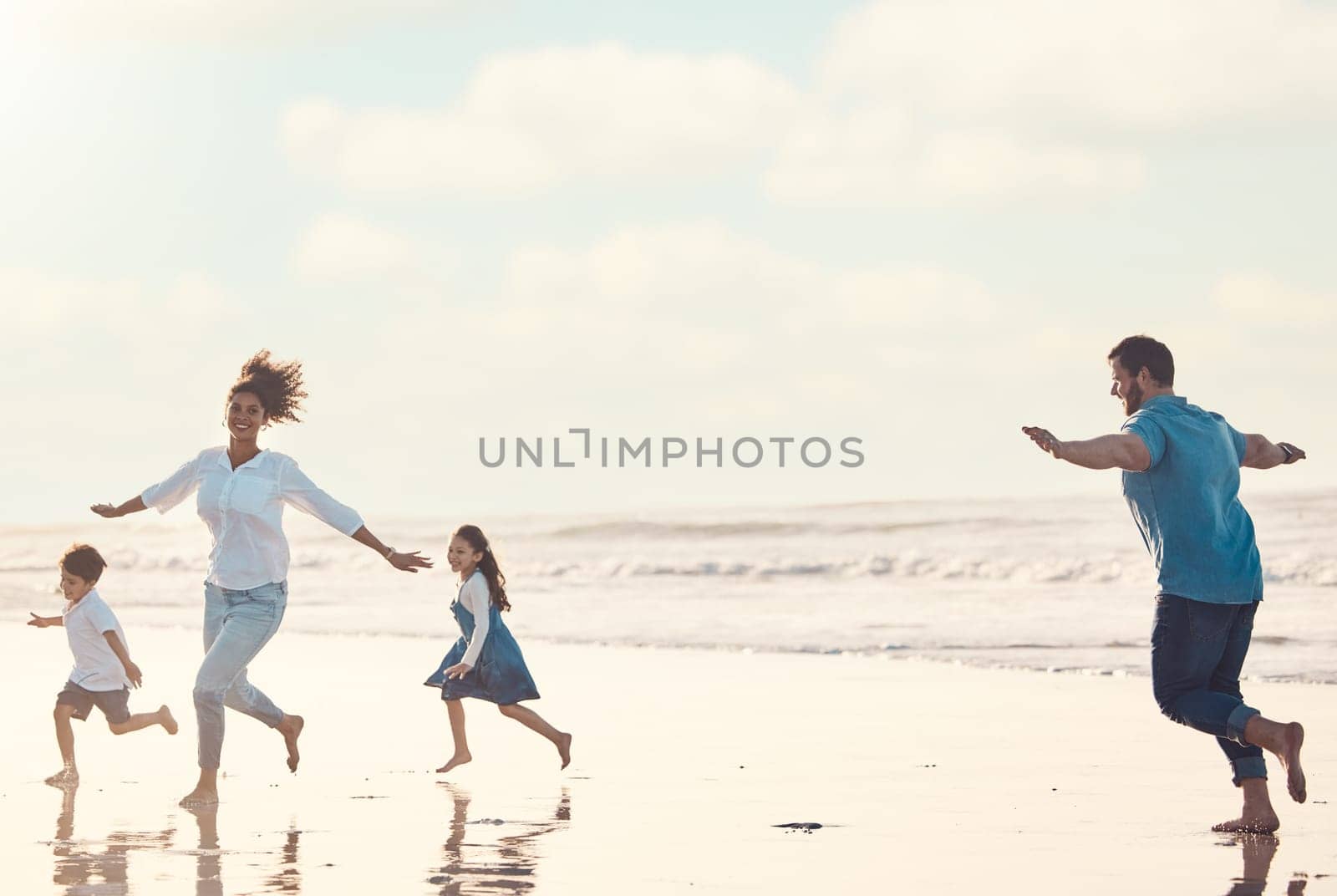 Mother, father and children on the beach to dance together while outdoor for travel or vacation in summer. Sunset, family or children and siblings having fun with parents on the coast by the ocean.