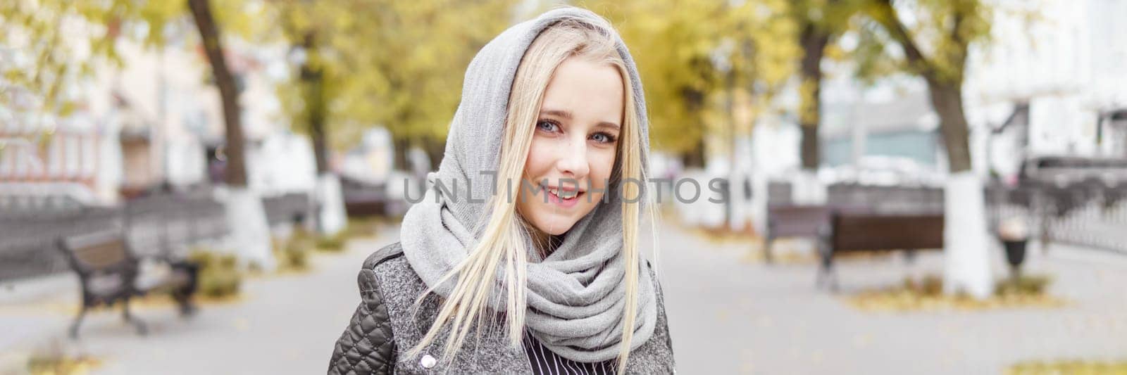 A young blonde walks through the autumn city in a gray coat. The concept of urban style and lifestyle