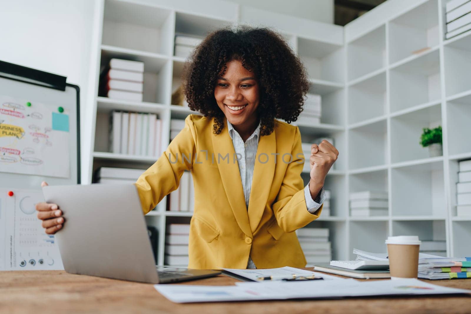 American African business woman using document, computer laptop, calculator, paperwork, documents, in winner and smiling Happy to be successful achievement success. finance and investment concepts by Manastrong