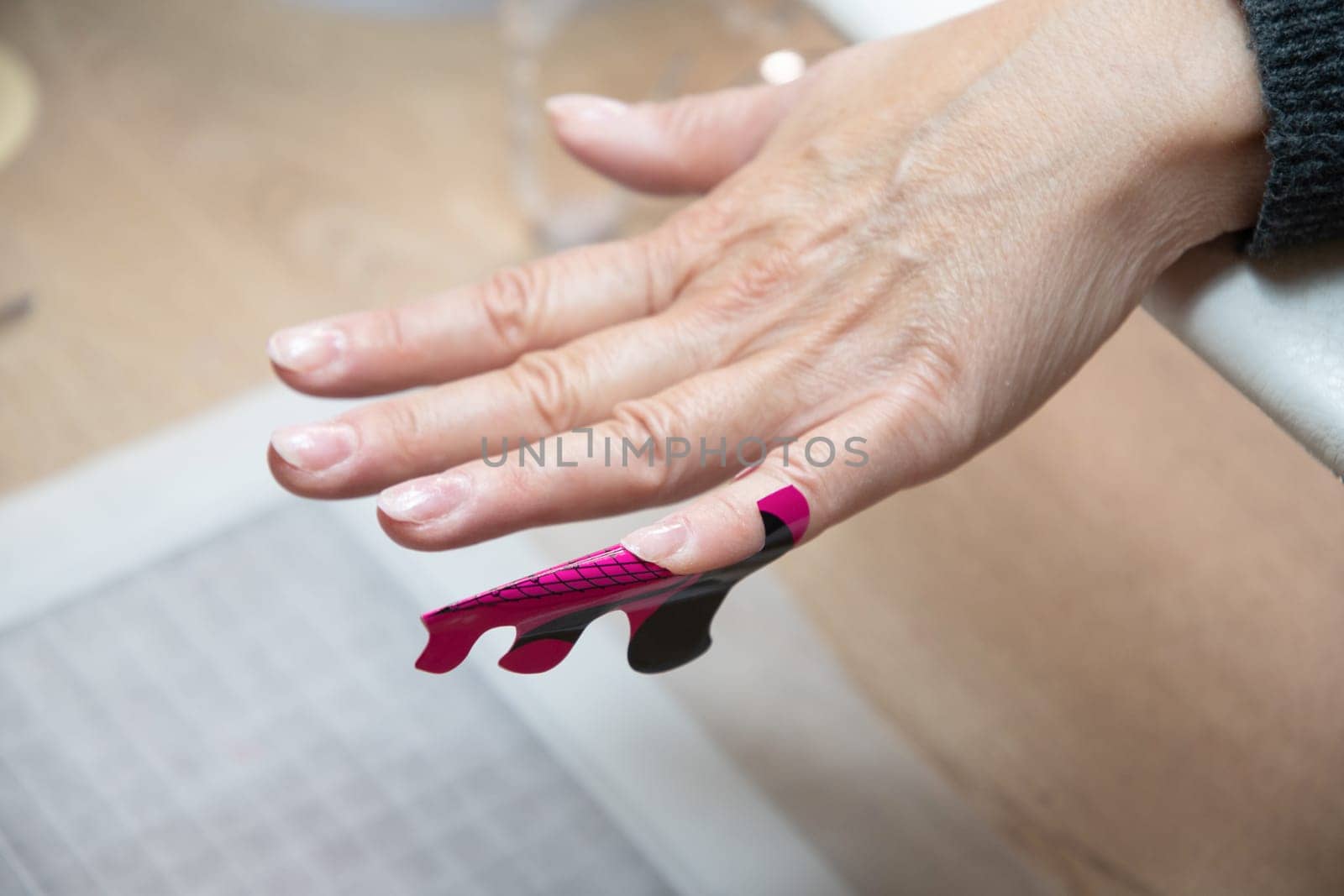 manicurist lengthens client's nails with acrylic builder gel sticker. High quality photo