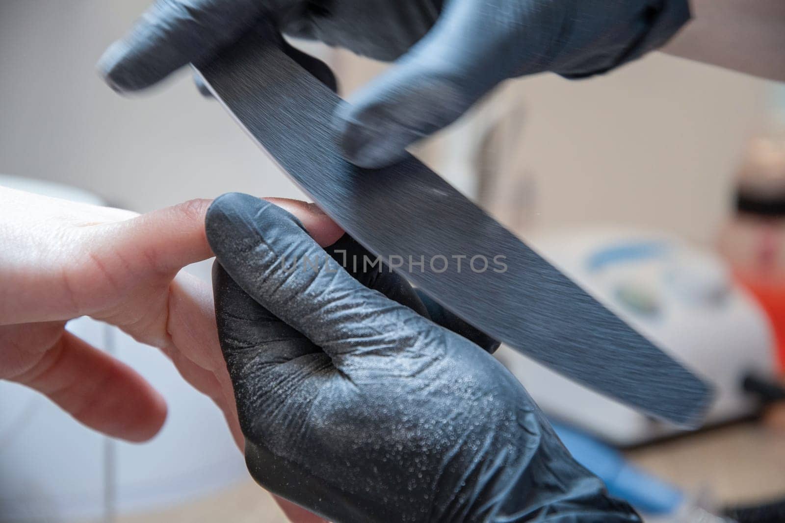 Skilled manicure master using fingernail file while correcting client nail form. High quality photo