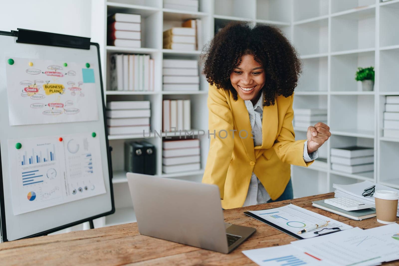 American African business woman using document, computer laptop, calculator, paperwork, documents, in winner and smiling Happy to be successful achievement success. finance and investment concepts by Manastrong