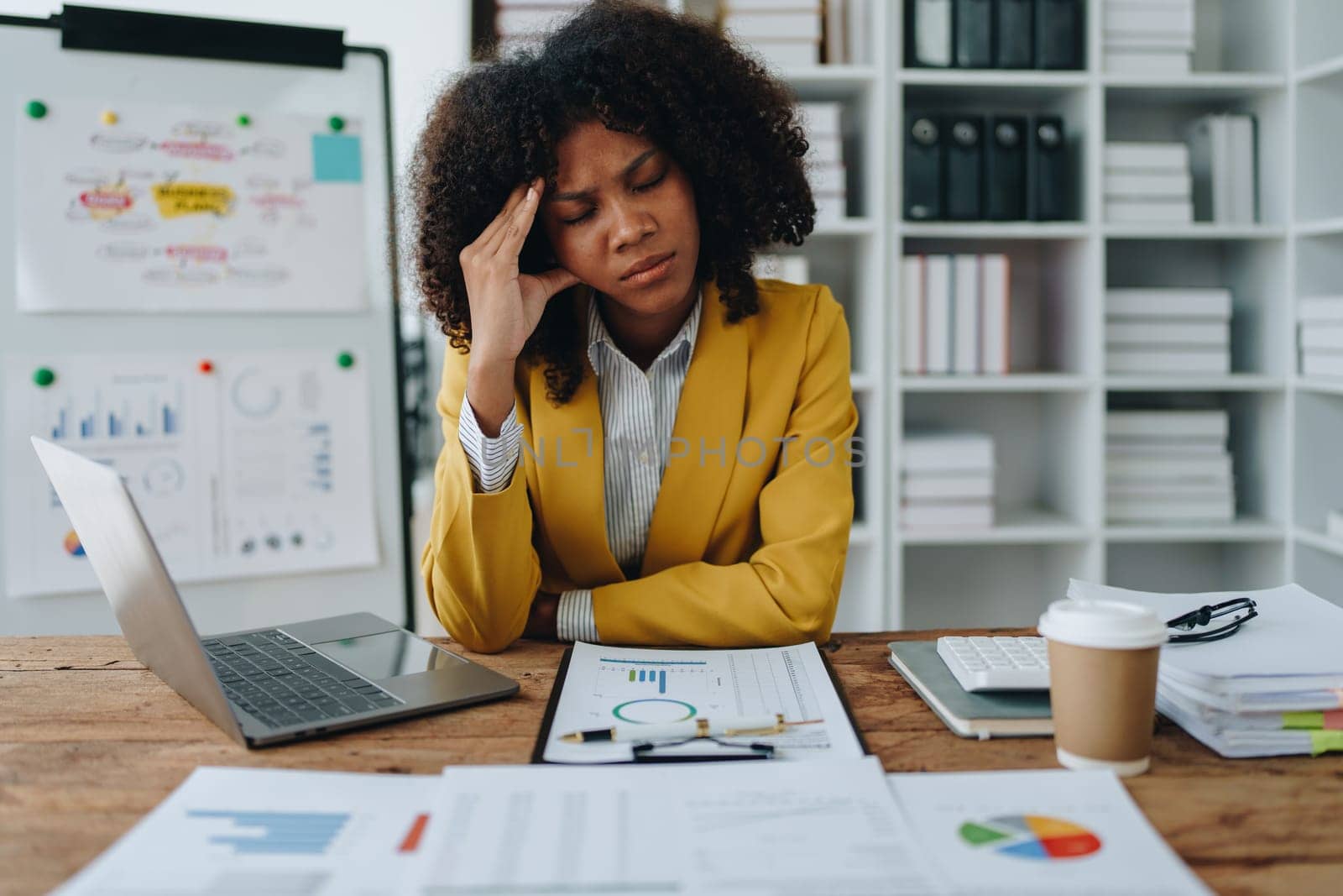 Burnout American African business woman in stress works with many paperwork document, migraine attack, Freelance, work at office.