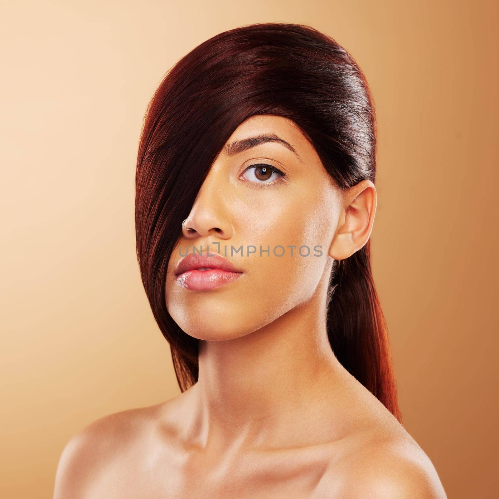 Hair care, beauty and portrait a young woman in studio for salon, hairdresser and wellness results. Glow, cosmetics and shampoo for growth and shine of serious model person on a brown background by YuriArcurs