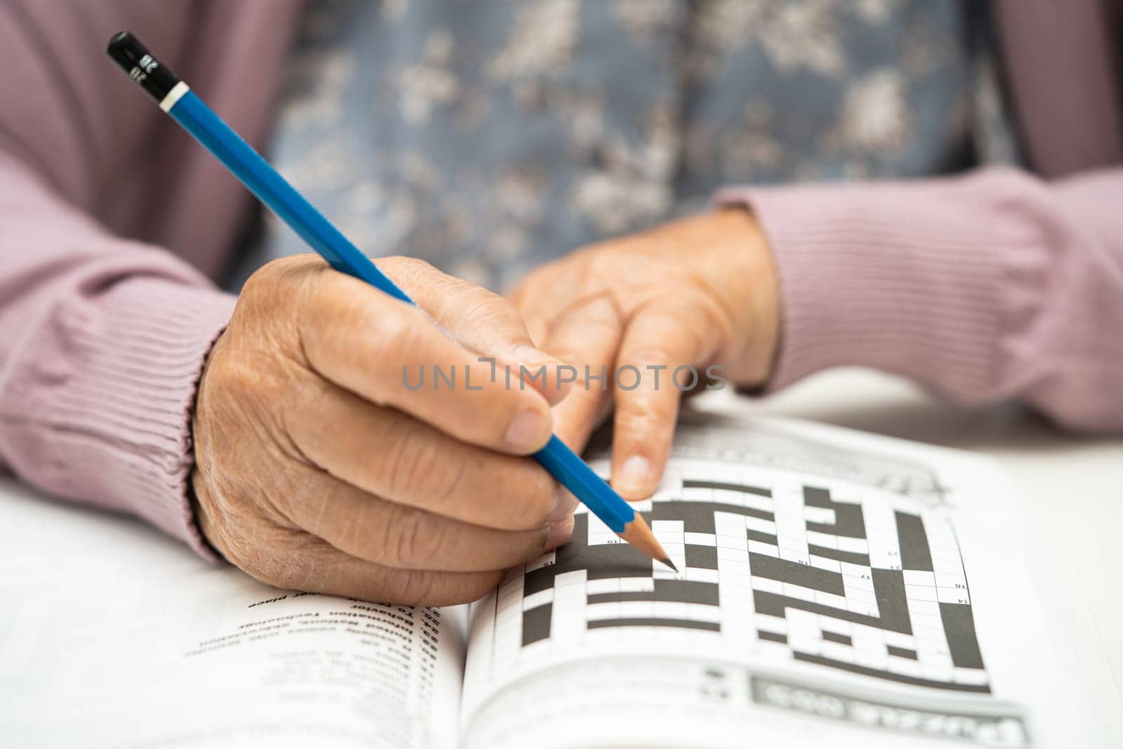 Alzheimer disease AD, Asian elderly woman playing sudoku puzzle game to practice brain training for dementia prevention.