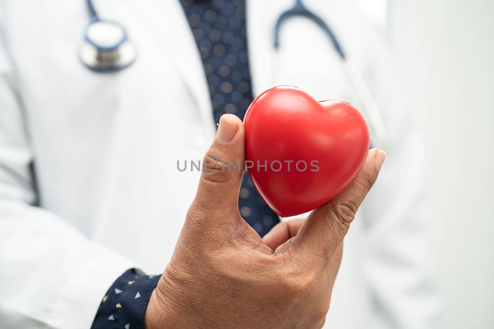 Doctor holding a red heart in hospital ward, healthy strong medical concept.