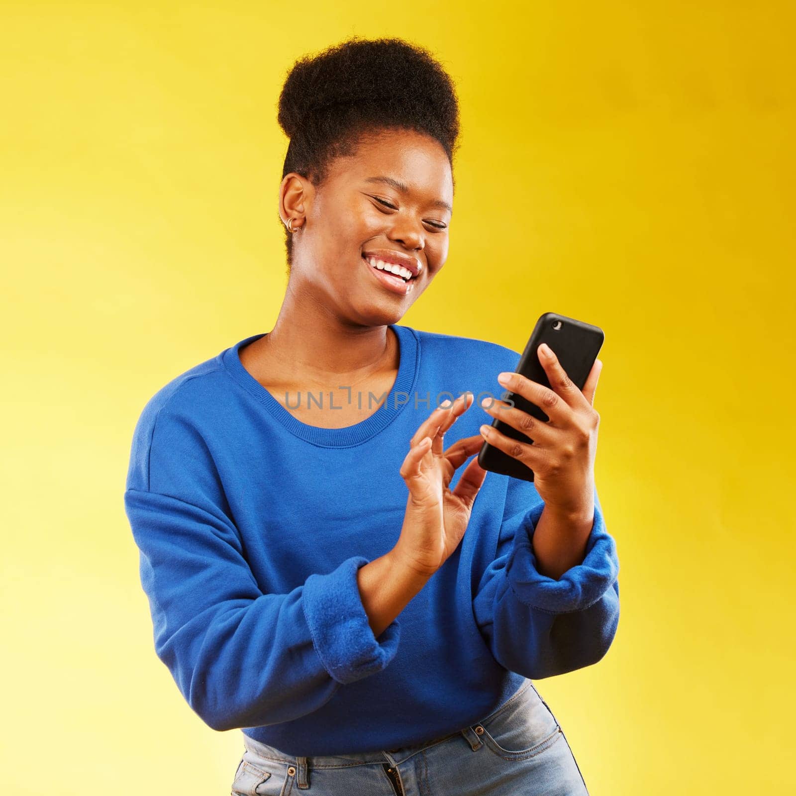 Happy black woman, phone and social media for networking or communication against a yellow studio background. African female person smile for online browsing or chatting on mobile smartphone app.