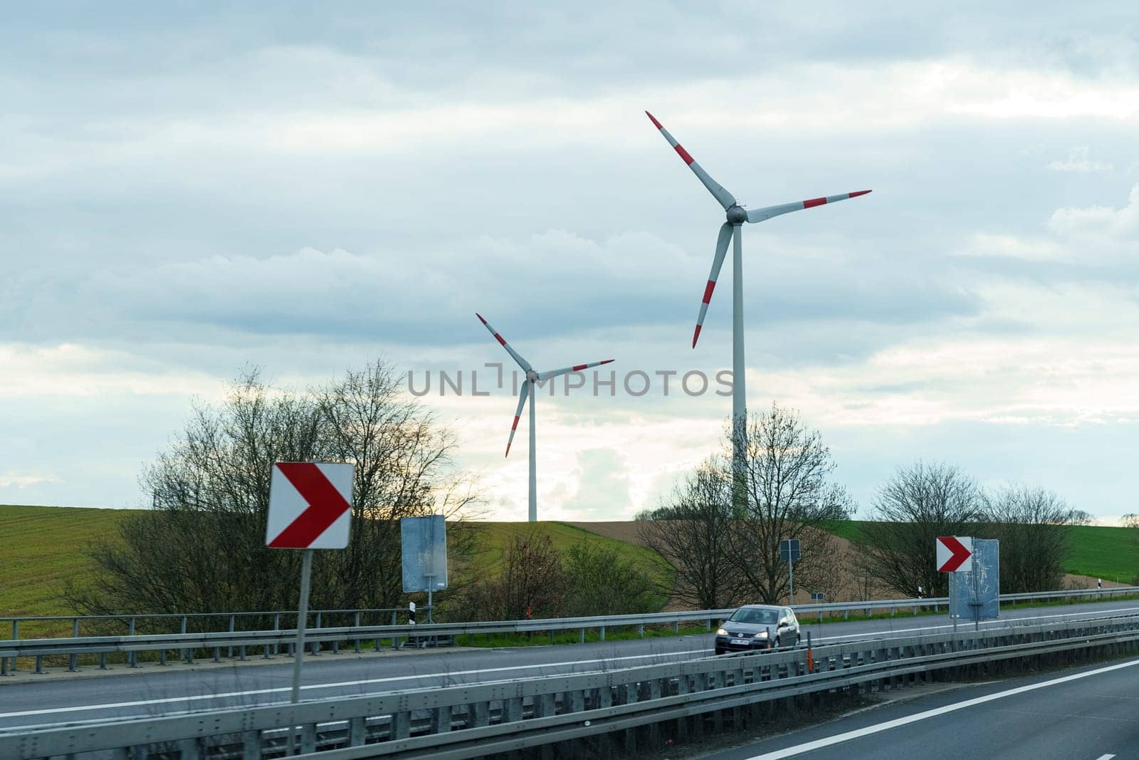 Dresden, Germany - April 24, 2023: Wind turbines stand along the highway along which the car moves.