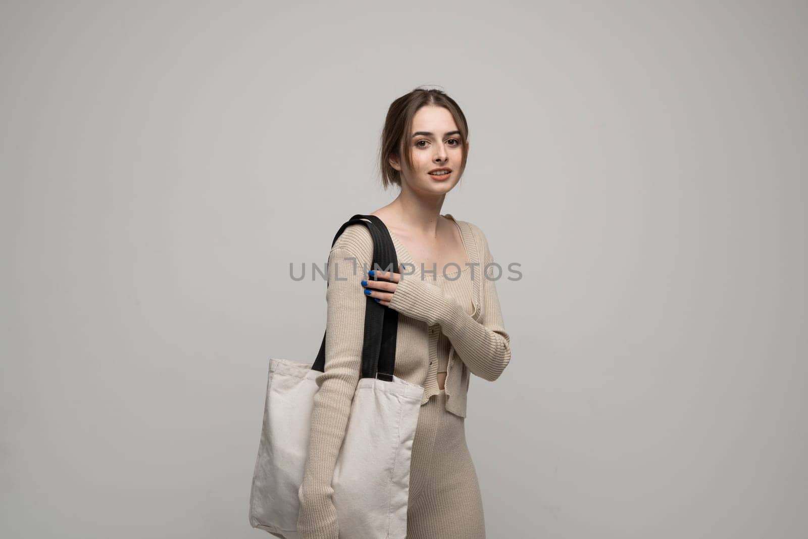 Happy, smiling brunette young woman carrying reusable cotton bag. Concept of recycle for better environment. No plastic