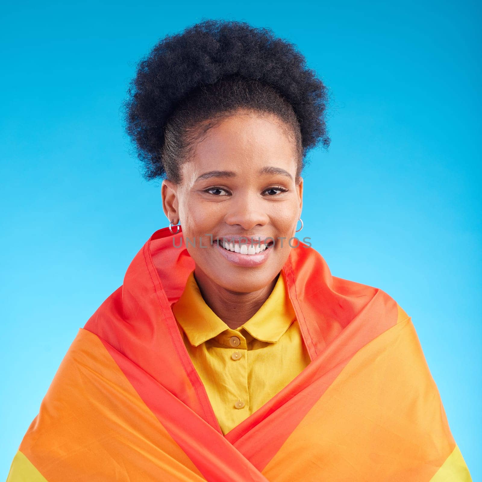 Pride, flag and portrait of black woman in studio for gay, rights and lgbtq lifestyle on blue background. Rainbow, freedom and face of lesbian African female happy, smile and confident with sexuality by YuriArcurs