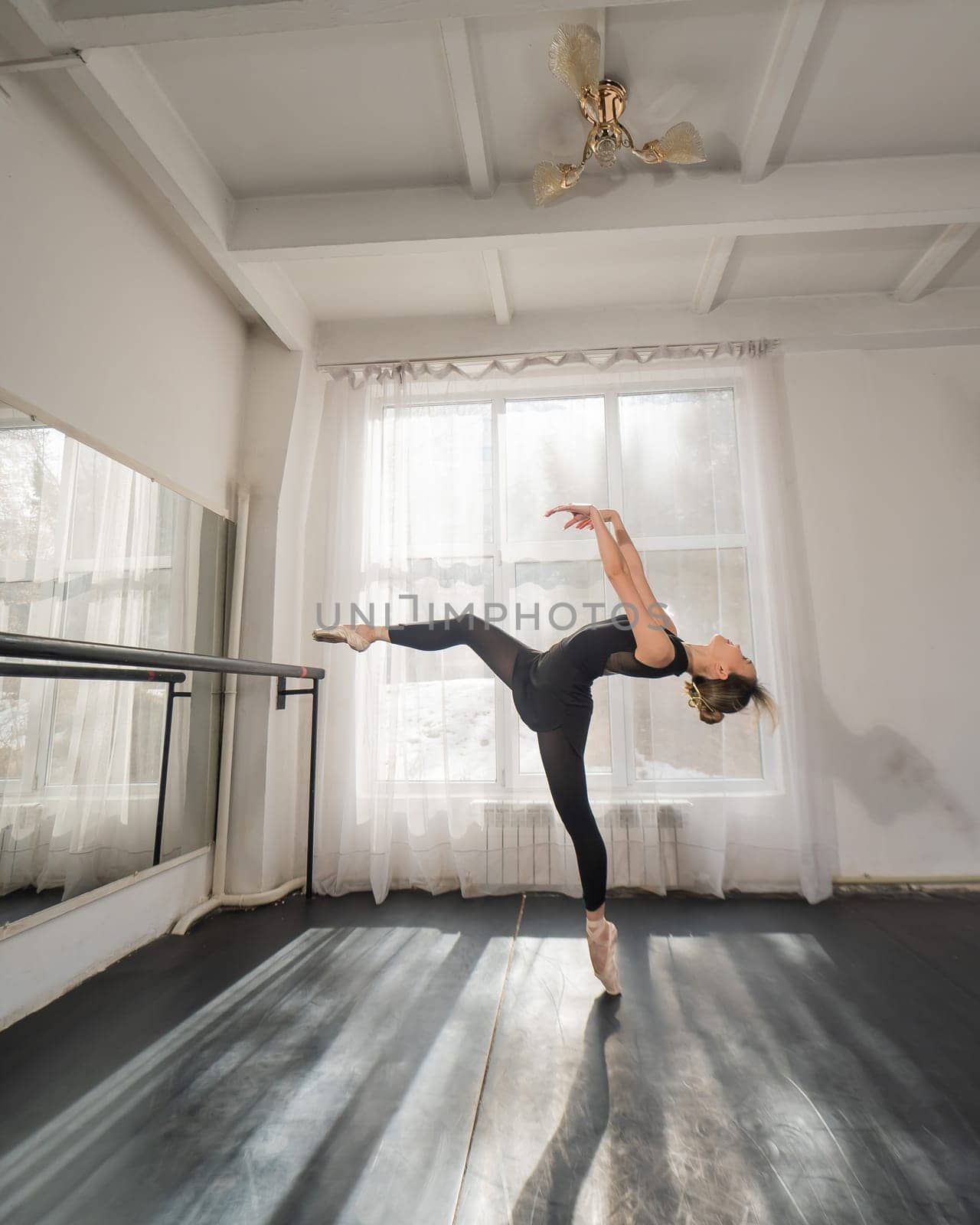 A beautiful Asian woman is dancing at the barre. Ballet dancer