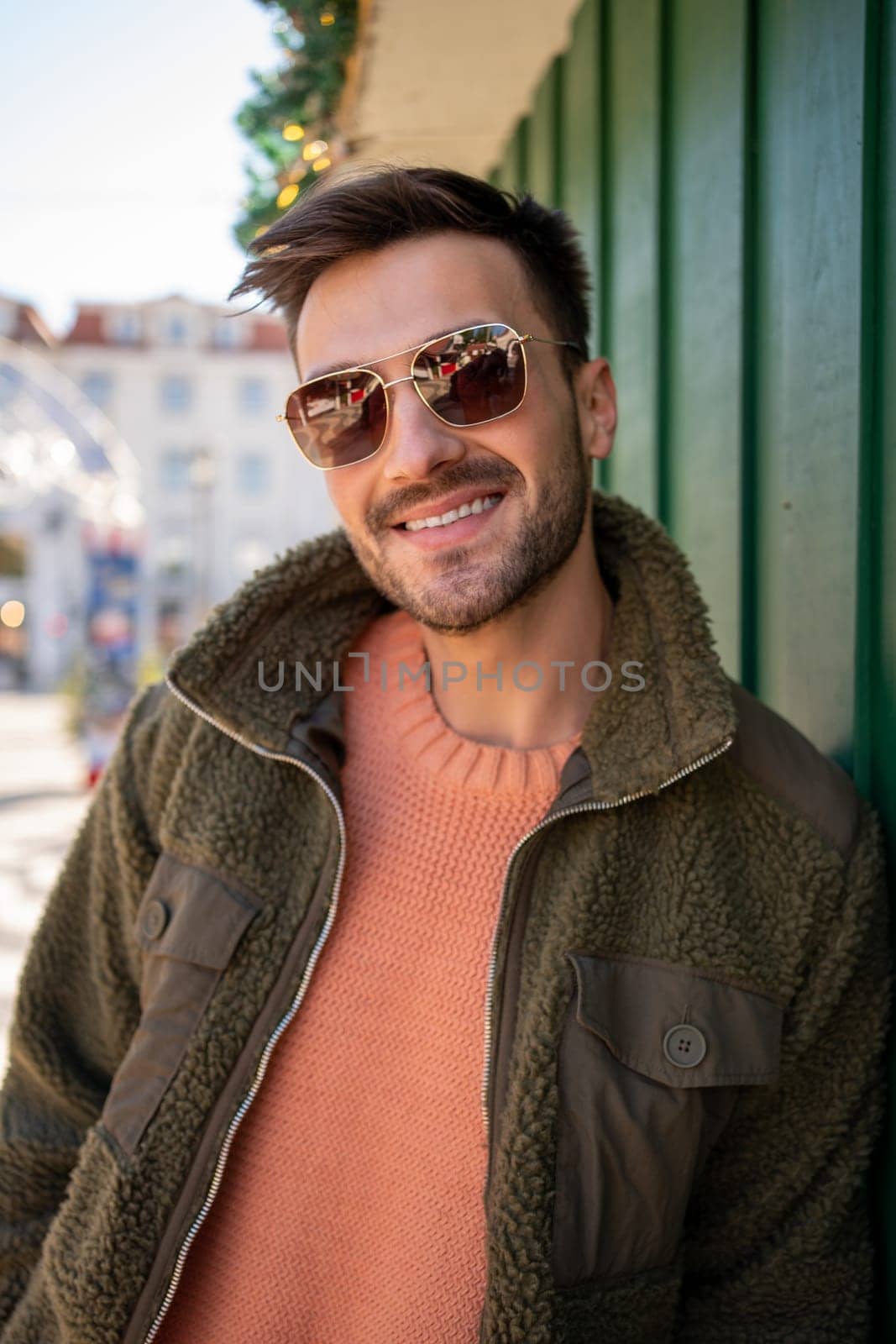 Handsome man wearing sunglasses standing outside looking camera and smiling. Close up portrait young bearded male person, vertical photo