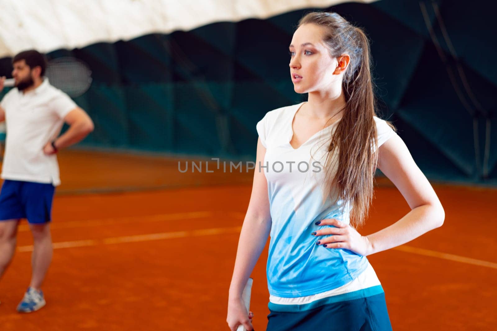 Young woman playing tennis at indoor tennis court by Fabrikasimf