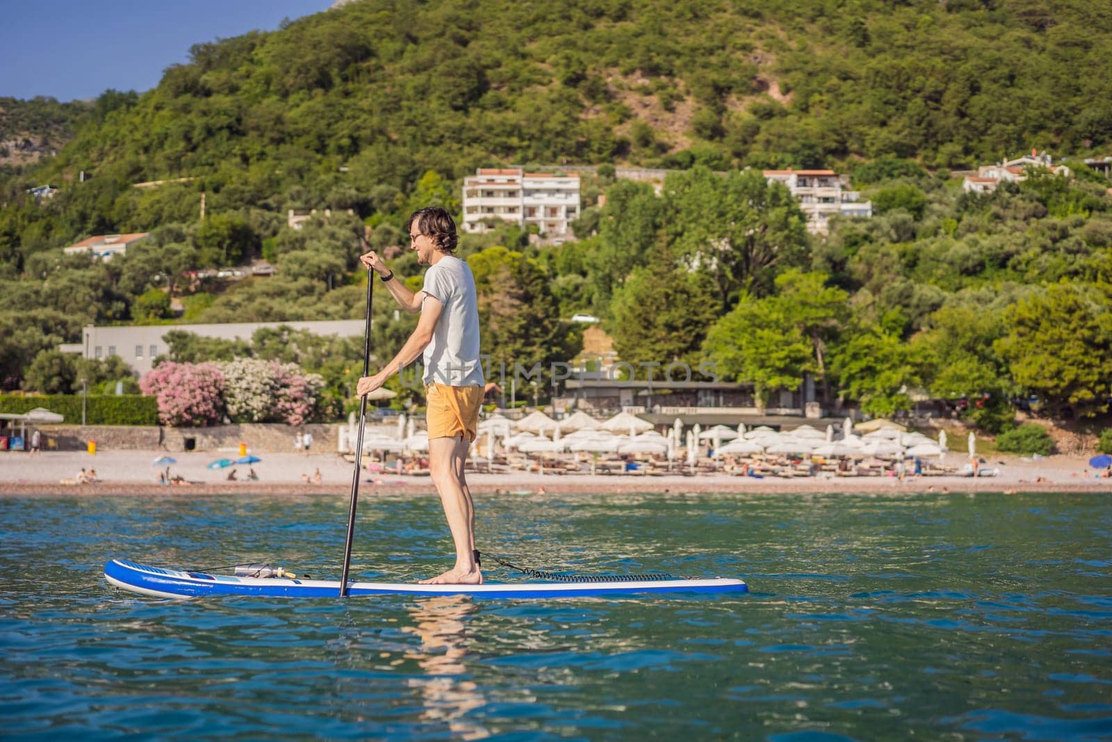 Young men Having Fun Stand Up Paddling in blue water sea near st stefan island in Montenegro. SUP.